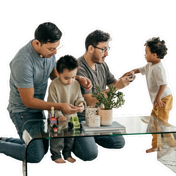 Two fathers and two young boys sitting at a coffee table playing with toys